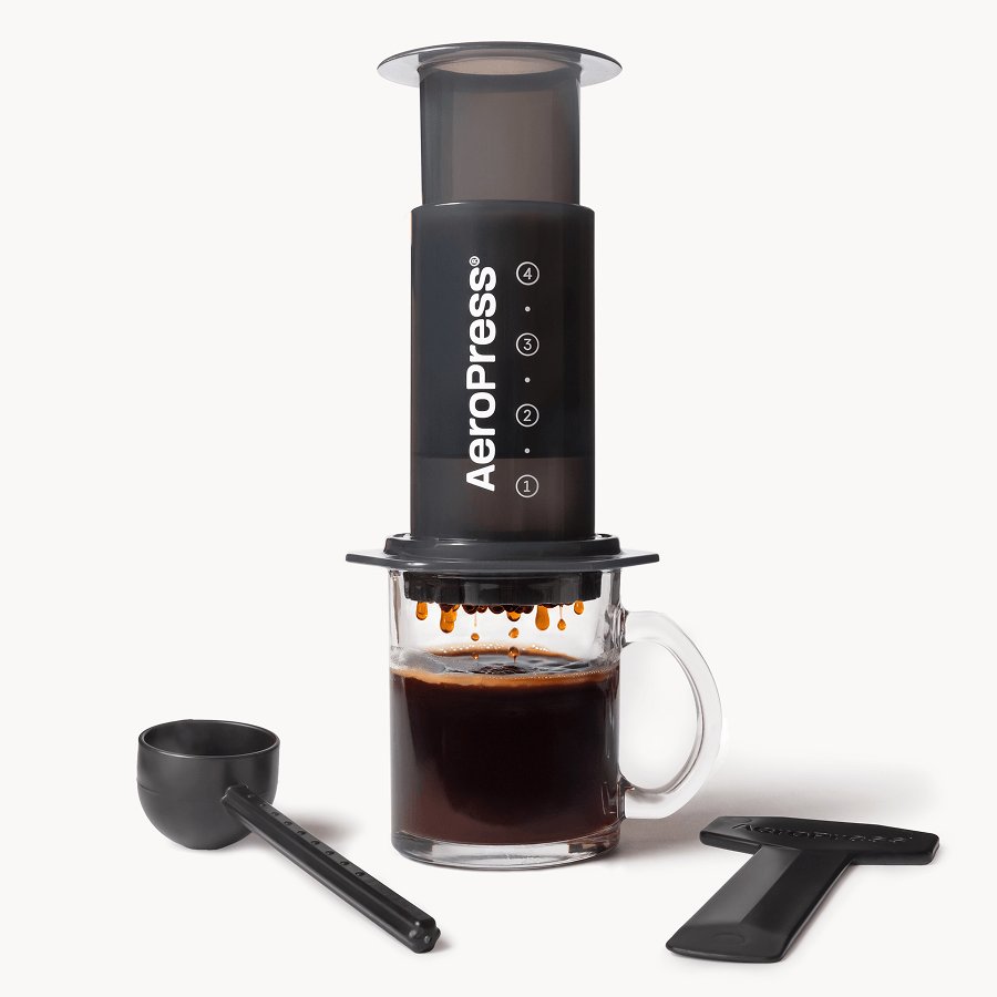 AeroPress Original coffee press on a mug, with its scoop and stirrer